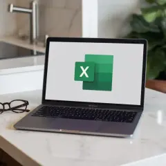 Laptop z logo Excel na ekranie, obok okulary.