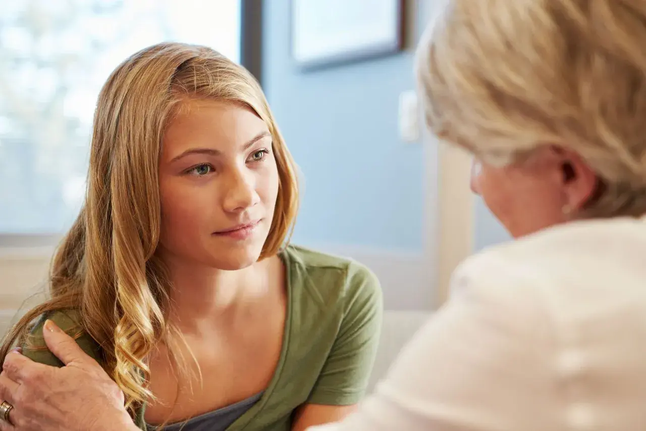 Dziewczyna rozmawia z psychologiem, który wspiera ją, dotykając ramienia. To pokazuje, czym zajmuje się psychologia kliniczna: pomaga w trudnych emocjach.