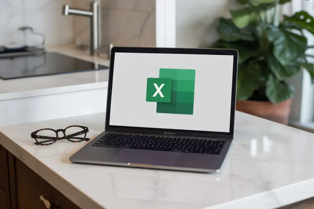 Laptop z logo Excel na ekranie, obok okulary.